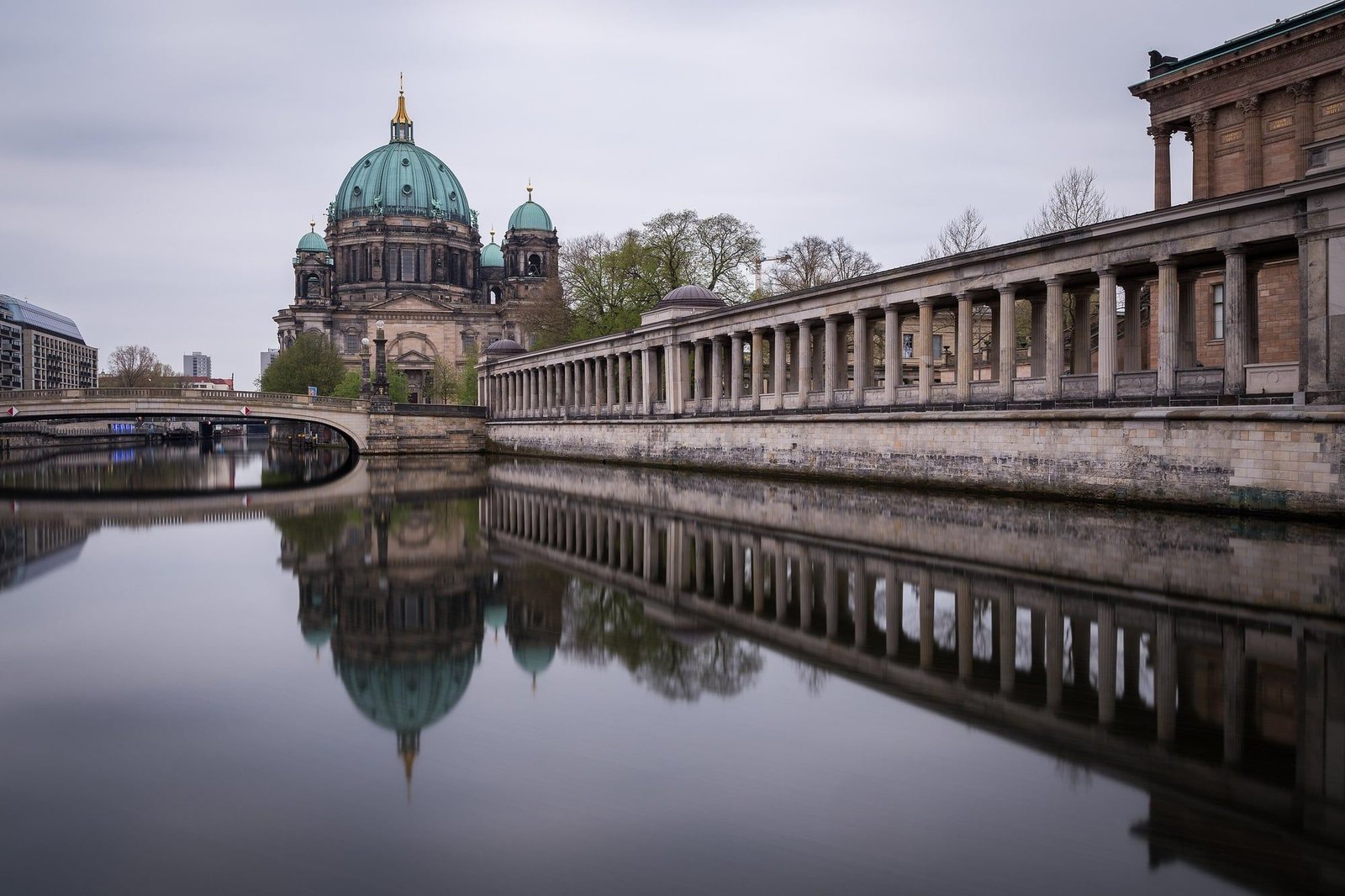 Berlin Cathedral and a riverside colonnade on Museum Island, reflected in the still Spree